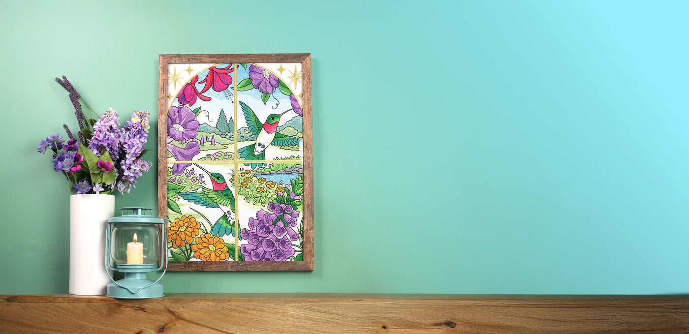 Framed machine embroidery design featuring hummingbird and flowers on a teal wall with a wooden shelf.