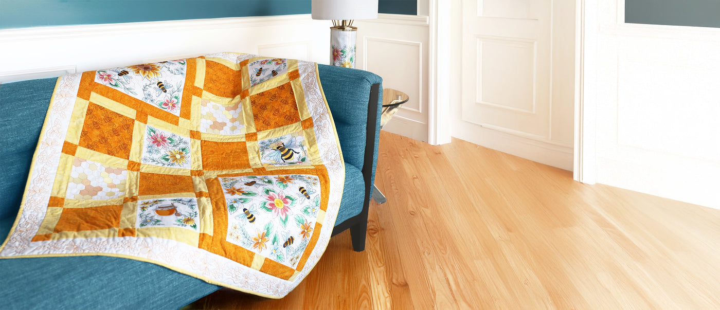 Machine embroidery quilt with bee and flower designs on a blue couch