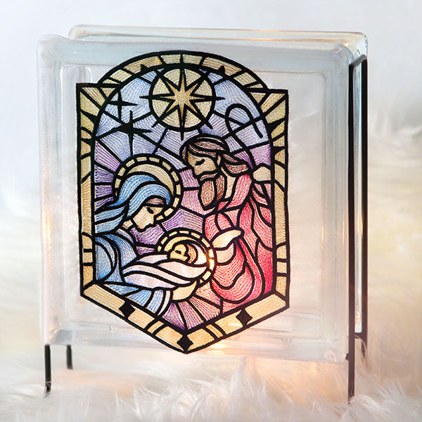 Glass block with machine embroidered stained-glass nativity design.