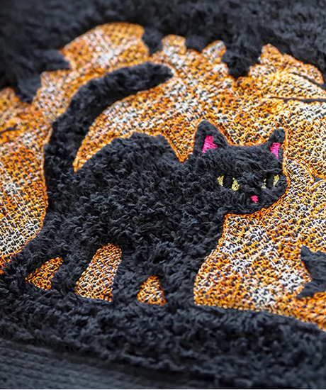 Black cat embossed machine embroidery design on a black textured fabric background