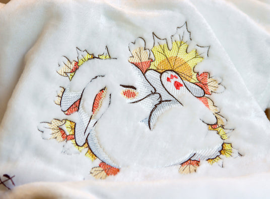Machine embroidered fall sleeping bunny design on a white blanket