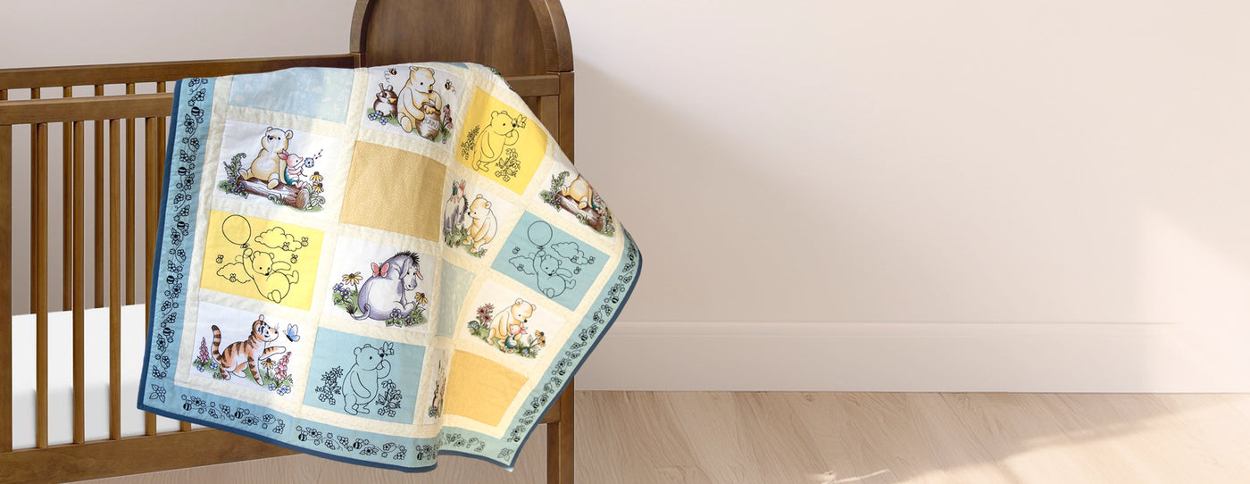 Machine embroidery pooh & friends designs on a children's quilt laying on a crib.
