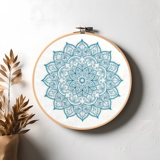 Machine embroidery mehndi design in a hand embroidery hoop on a white wall.