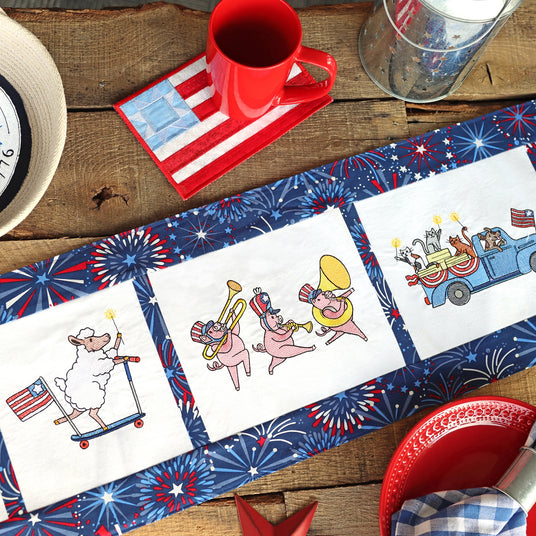 Table setting with placemats featuring machine embroidery patriotic designs, a red mug on a wooden surface.