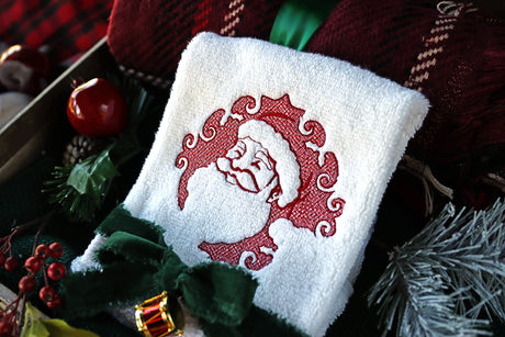 White towel with machine embroidery embossed Santa surrounded by Christmas decor