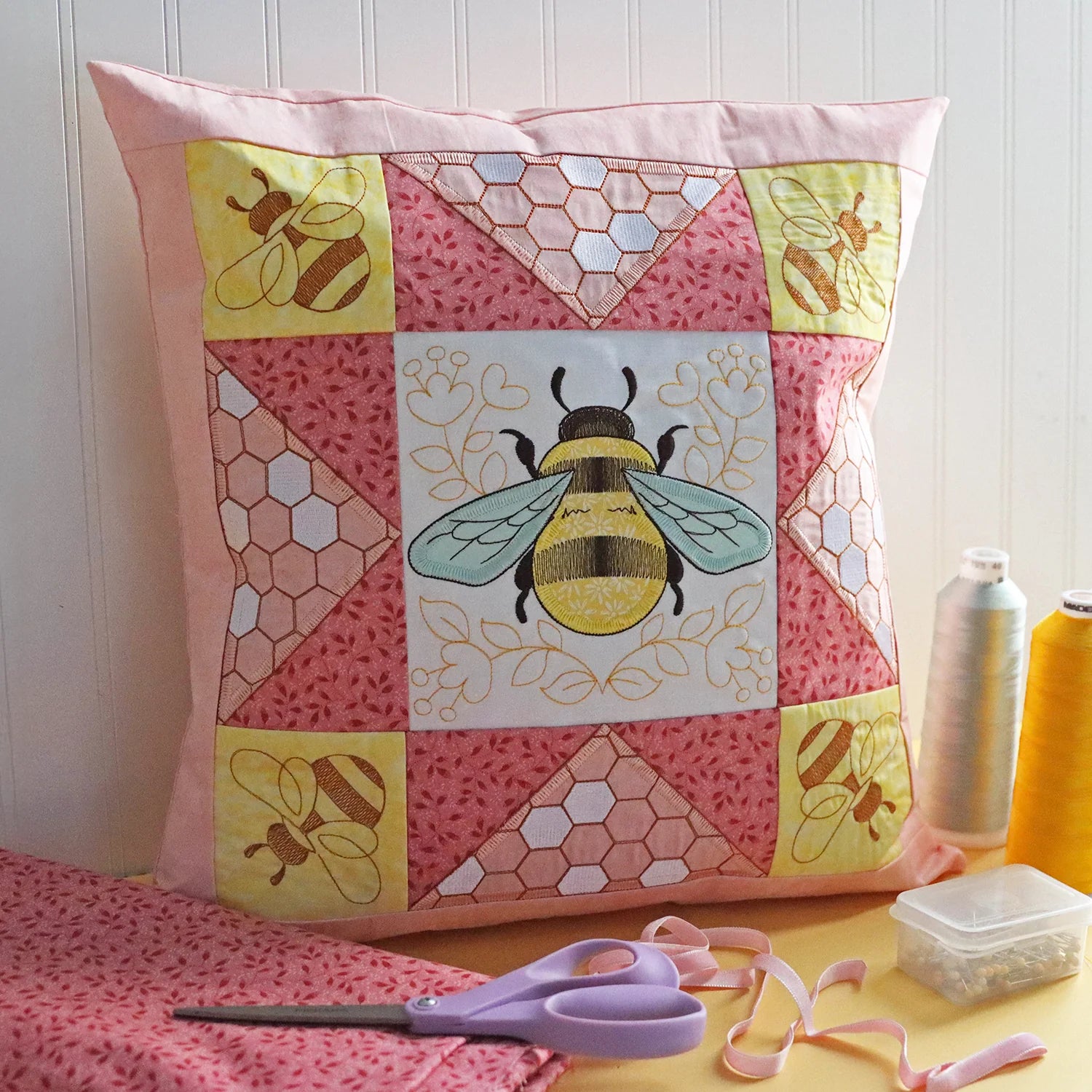 a multi-piece quilt block pillow featuring a machine embroidered bee design