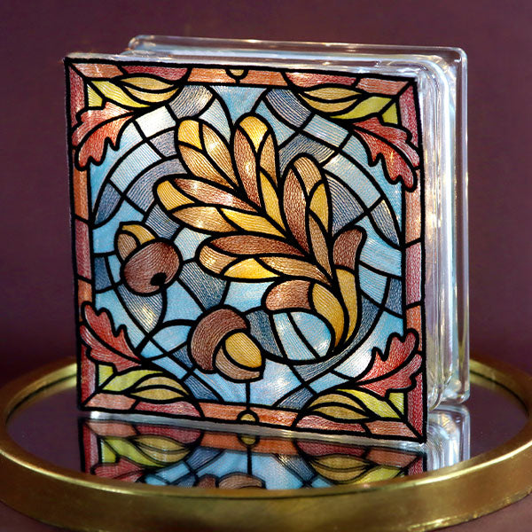 stained glass machine embroidery design of a leaf shown on a lit glass block