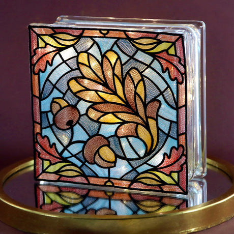 stained glass machine embroidery design of a leaf shown on a lit glass block