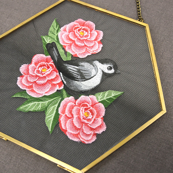 machine embroidery design of a chickadee and flowers stitched on nylon screen in a gold geometric frame