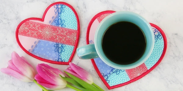 Completed Crazy Patchwork Trivet project, featuring Winged Whimsy Butterfly (In-the-Hoop) design, in a coffee place setting with tulips