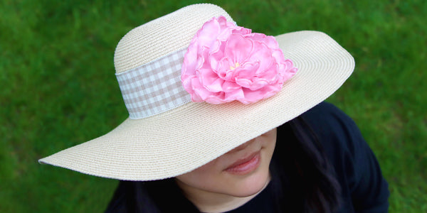Woman wearing a brimmed woven hat, sporting the completed 3D Freestanding Fabric and Lace Flower design in pink