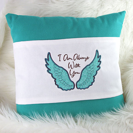 a pillow featuring a machine embroidery design of angel wings and the text "I am always with you"