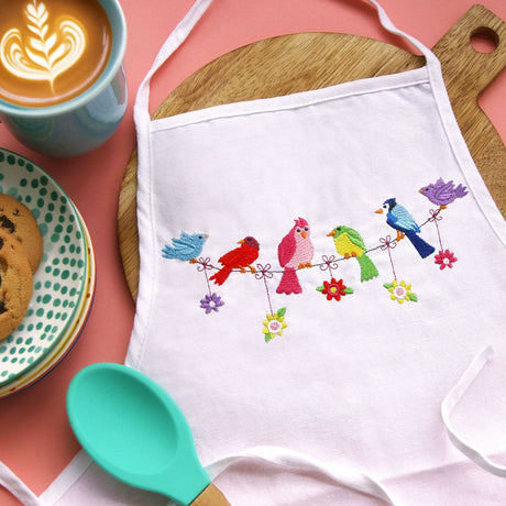 Digitally downloadable machine embroidery design showing embroidered birds perched on a clothesline on fabric.