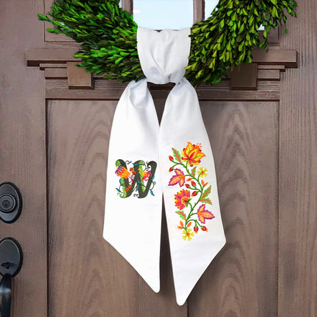 a wreath sash featuring machine embroidery designs of a monogram and a floral spray