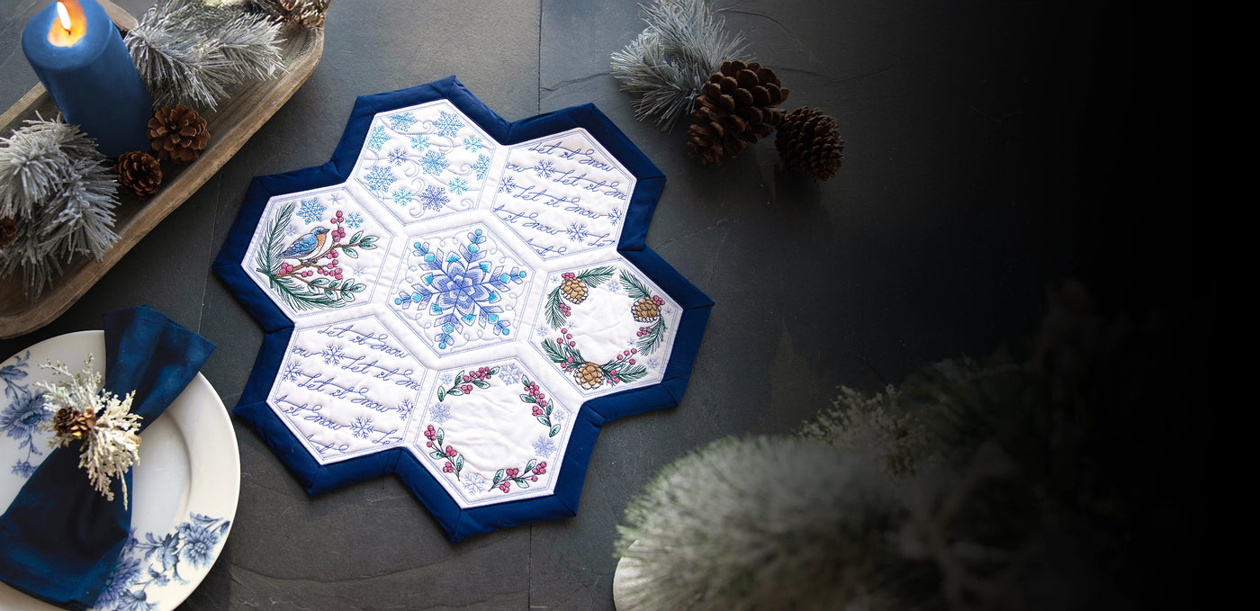 Decorative winter machine embroidery hexagon quilt designs on a granite background surrounded by winter decor.