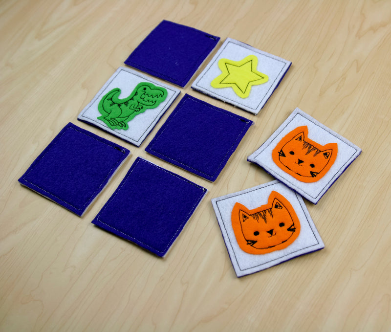 Set of machine embroidered felt squares with dinosaur, cats, and star on a wooden table.