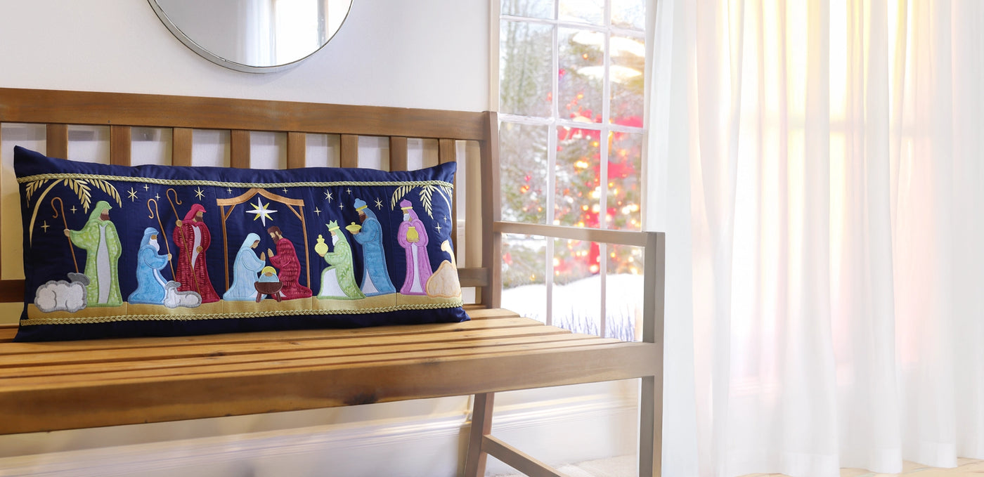 Machine embroidered applique Nativity scene design on pillow resting on a bench