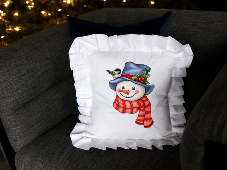Machine embroidery snowman on white pillow on a grey chair