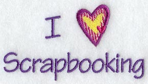 Purple and yellow embroidery spells I Love Scrapbooking with a heart motif on white fabric; machine embroidery design.