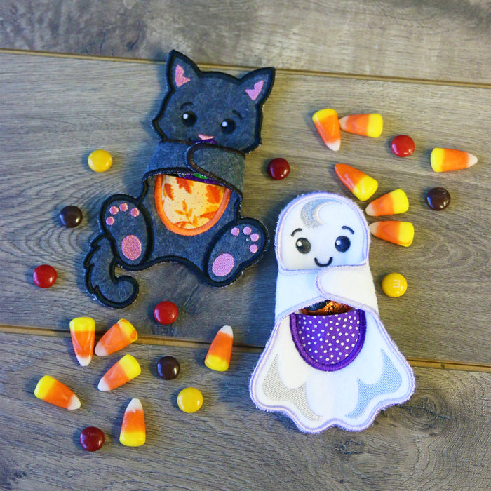 Halloween-themed cat and ghost candy holder with candy corn and chocolate candies on a wooden surface.