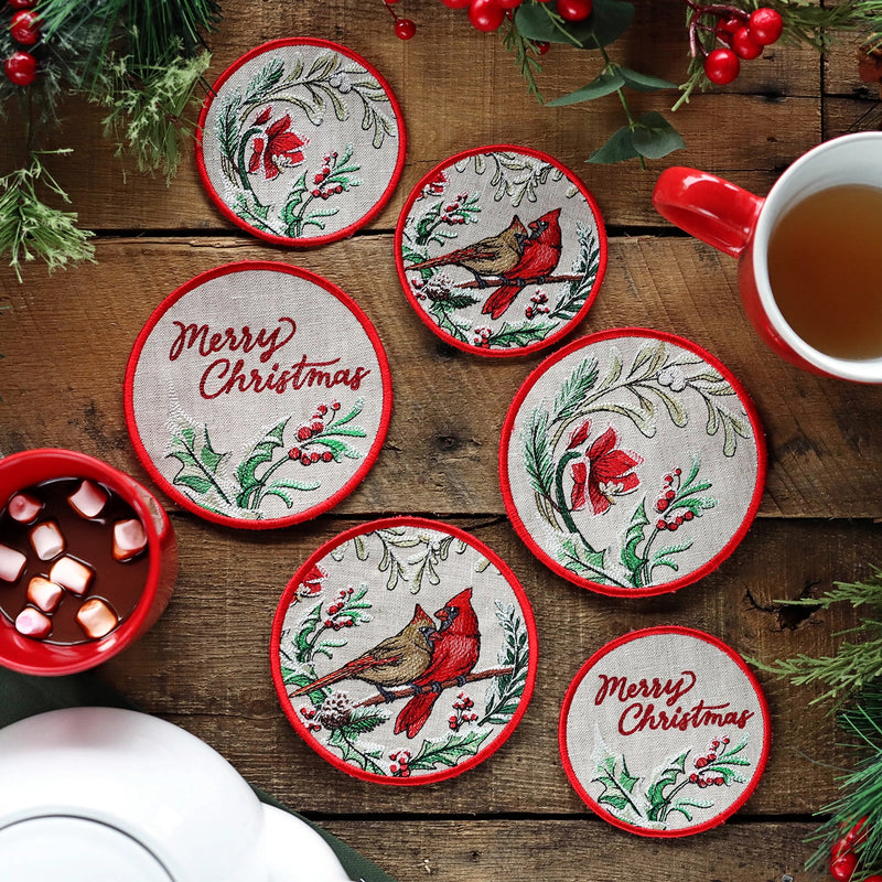 Set of Christmas-themed machine embroidered coasters on a wooden surface with a cup of tea and hot chocolate.