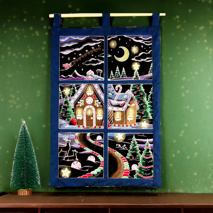 Machine embroidered Christmas gingerbread panel scene hanging on a green background.