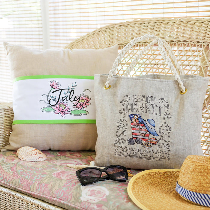 Beach-themed machine embroidered pillow and tote bag, staged with sunglasses, and hat on a wicker chair.
