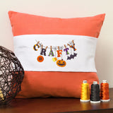Halloween motifs embroidered in orange and black thread on a pillow, with visible stitching and decorative accents.