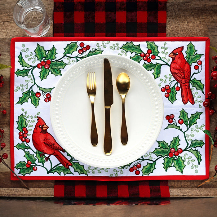Christmas-themed machine embroidered placemat with cardinals and holly design on a table setting.