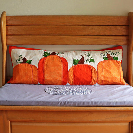 Decorative pillow with embroidered pumpkins on a wooden bed