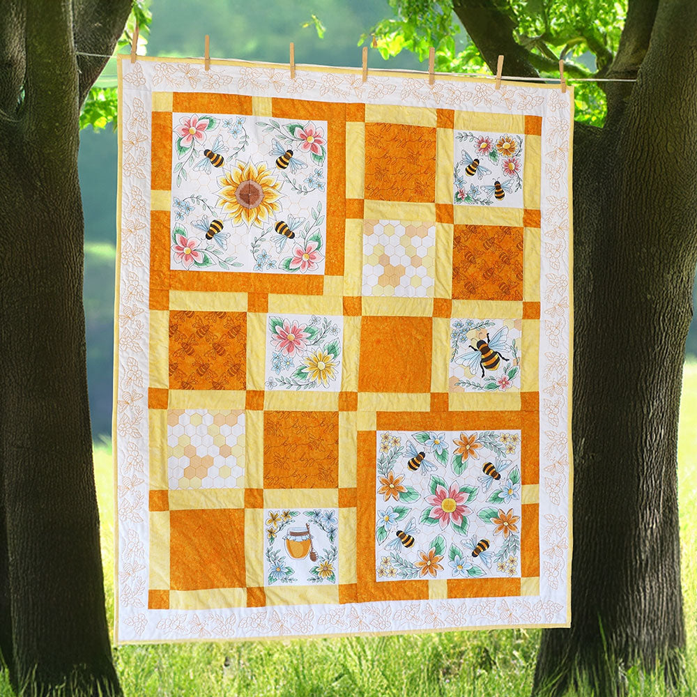 Quilt with bee and flower machine embroidery designs hanging between two trees outdoors
