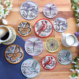 Set of decorative machine embroidered coasters with animal illustrations on a wooden table with a cup of coffee and milk pitcher.