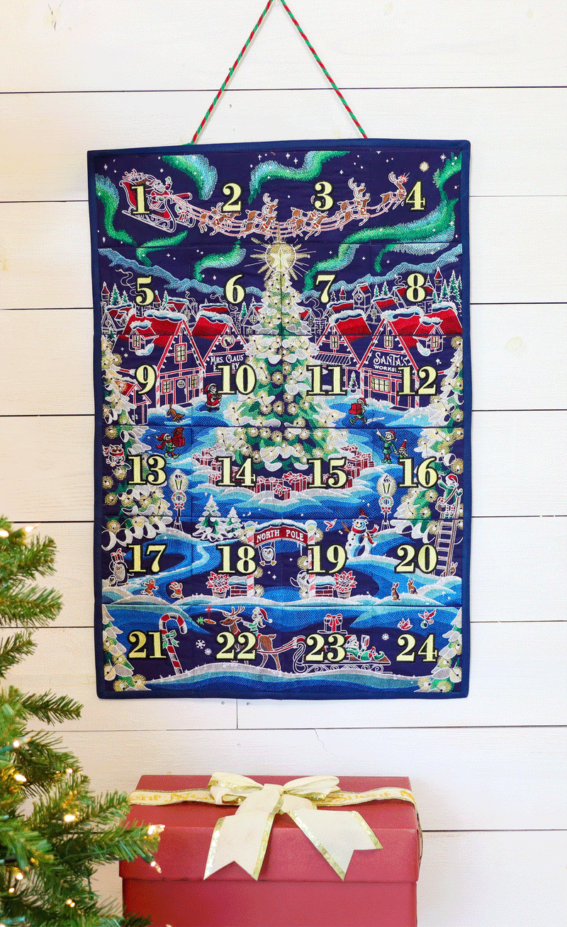 A machine embroidered advent calendar wall hanging with a hand removing various machine embroidered ornaments from the pockets.