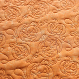 Orange fabric embroidered with jack-o-lantern faces and swirling patterns; a digitally downloadable embroidery Design Pack.