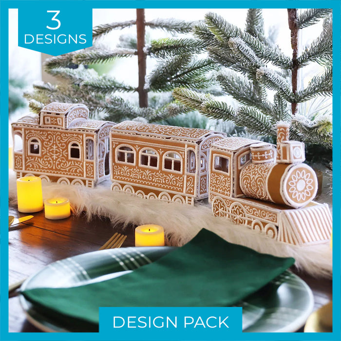 A gingerbread train with white icing decorations sits on a table runner with small lit candles and green pine branches behind it.