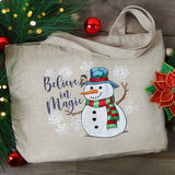 Digitally downloadable machine embroidery design of a snowman wearing a blue hat and red-green scarf, surrounded by snowflakes and the text "Believe in Magic.