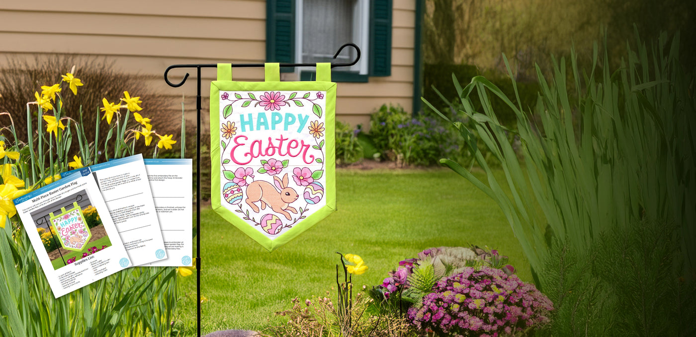Machine embroidered Happy Easter garden flag with a bunny design on a lawn with flowers and a house in the background.