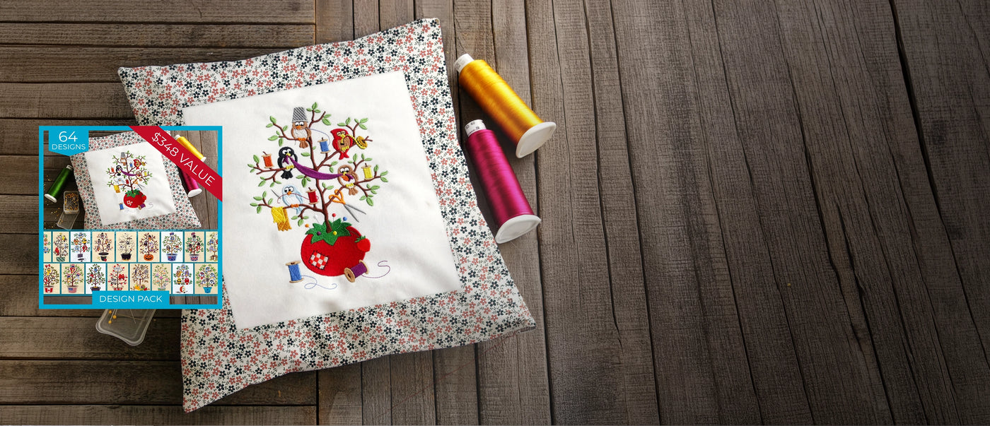 Decorative pillow with machine embroidered sewing-themed bird tree design resting on a wood surface beside colorful thread spools, with matching design pack preview shown on the left.