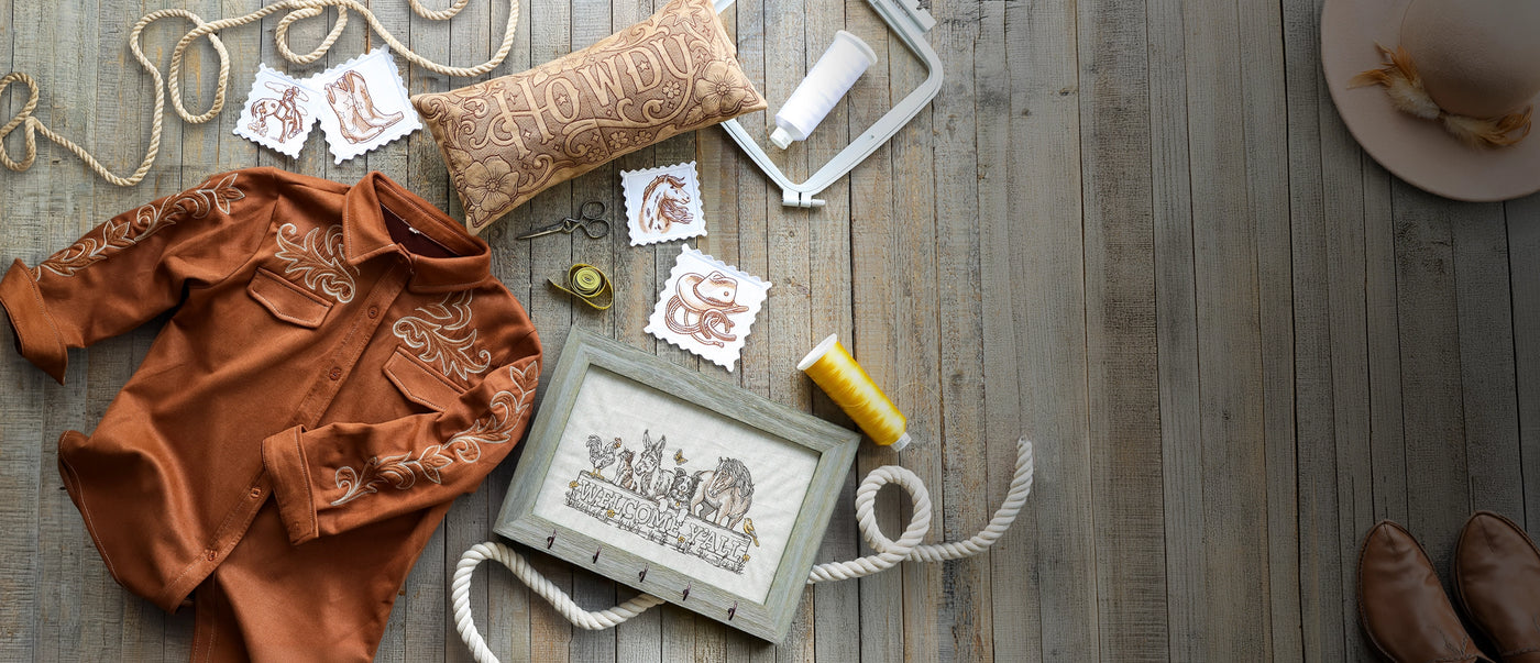 Machine embroidered brown shirt, coasters, pillow and a framed picture on a wooden surface.