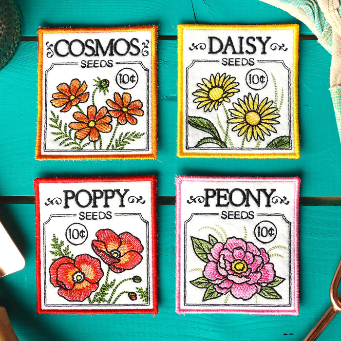 Four machine embroidered flower seed packet coasters on a teal background