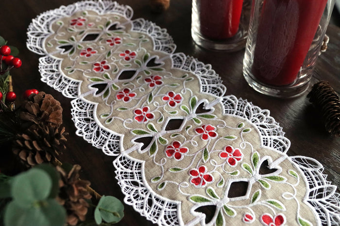 Decorative machine embroidered lace table runner with floral patterns on a wooden surface.