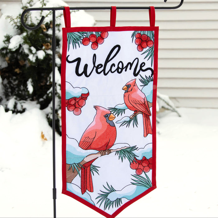 Decorative machine embroidery garden flag with cardinals and 'Welcome' text in front of a house with snow on the ground.