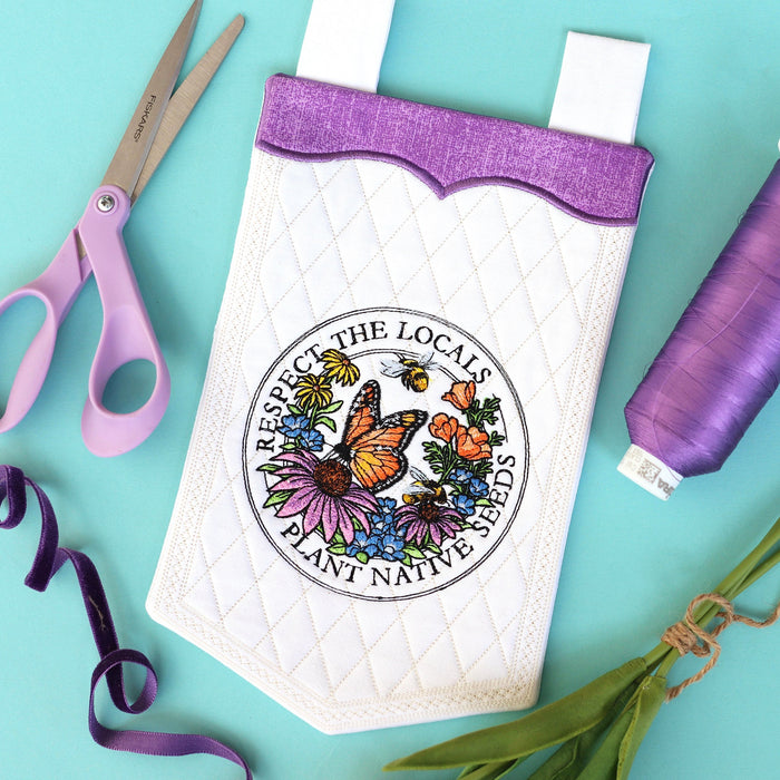 Machine embroidery banner with respect the locals design next to scissors and thread.