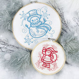 Two digitally downloadable machine embroidery designs shown in hoops featuring a doodle snowman in blue and a Santa Claus in red with decorative swirls.