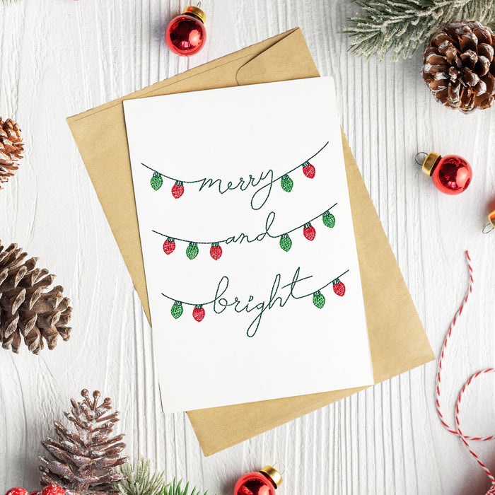 Digitally downloadable machine embroidery design featuring Merry and Bright stitched with festive motifs on cardstock.