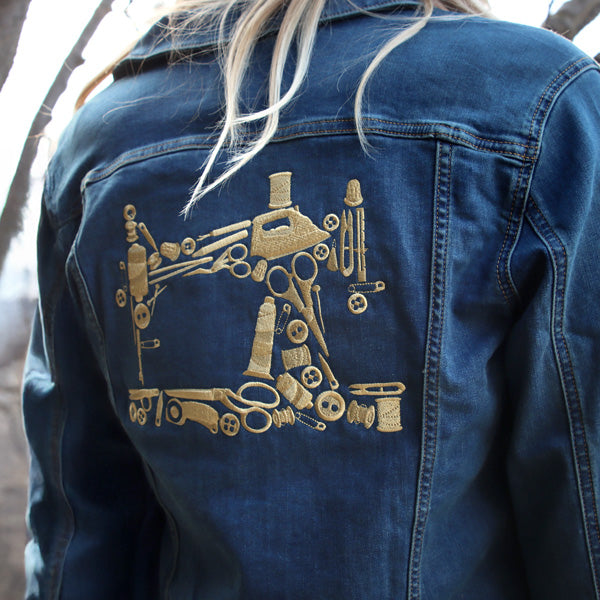 Blue denim jacket with gold machine embroidered design of a robot and tools on the back.