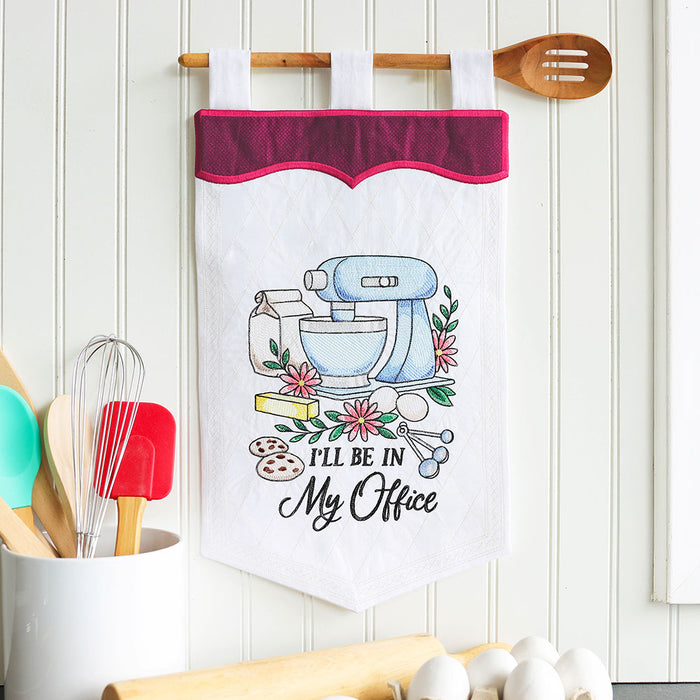 Machine embroidery baking design with text 'I'll be in my office' on a white hanging banner in a kitchen.