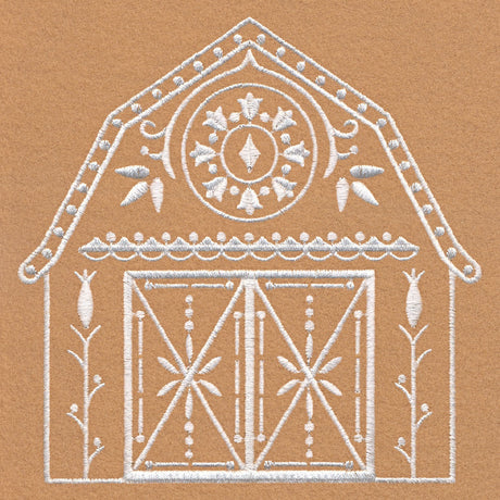 White embroidery of a decorative barn with patterned double doors, floral accents, and a circular floral motif on the roof, stitched on tan fabric.