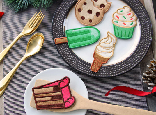 Machine embroidered play food - cookies, popsicle, ice cream cone, cupcake, and cake on plates surrounded by spoons and forks.