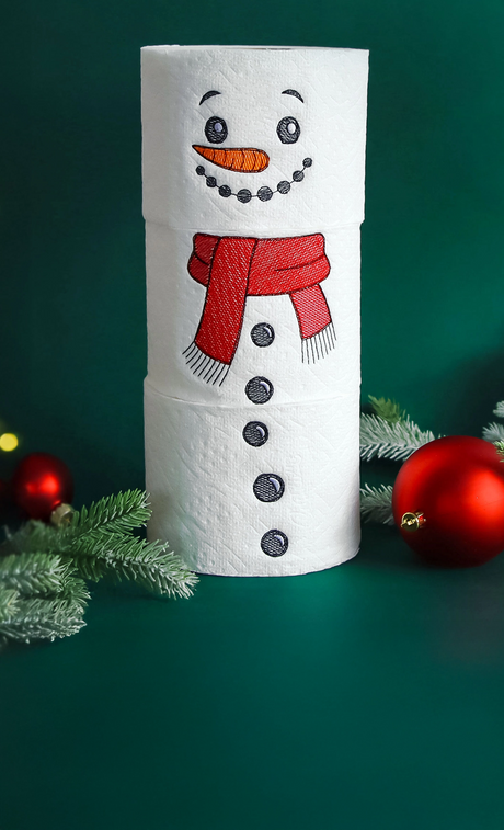 Decorative machine embroidery stackable snowman on toilet paper surrounded by Christmas decor.